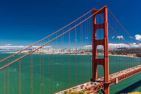 Golden-gate-bridge-closeup-showing-water-and-blue-skies-in-background-with-cars-crossing-the-bridge