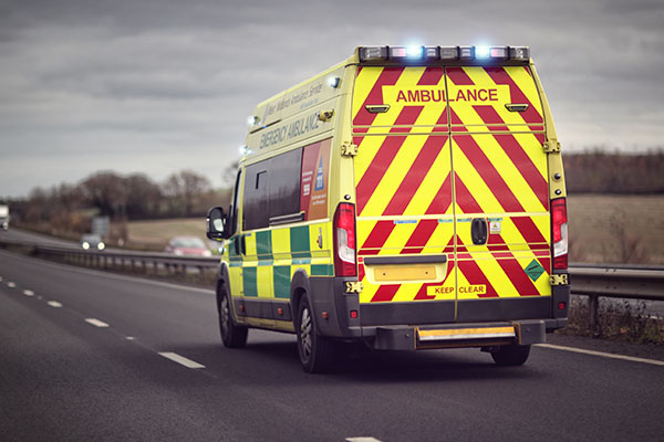 Yellow-ambulance-driving-quickly-down-highway-to-emergency-with-flashing-lights-on-showing-support-and-need-for-quicker-response-times-with-next-generation-9-1-1-technology