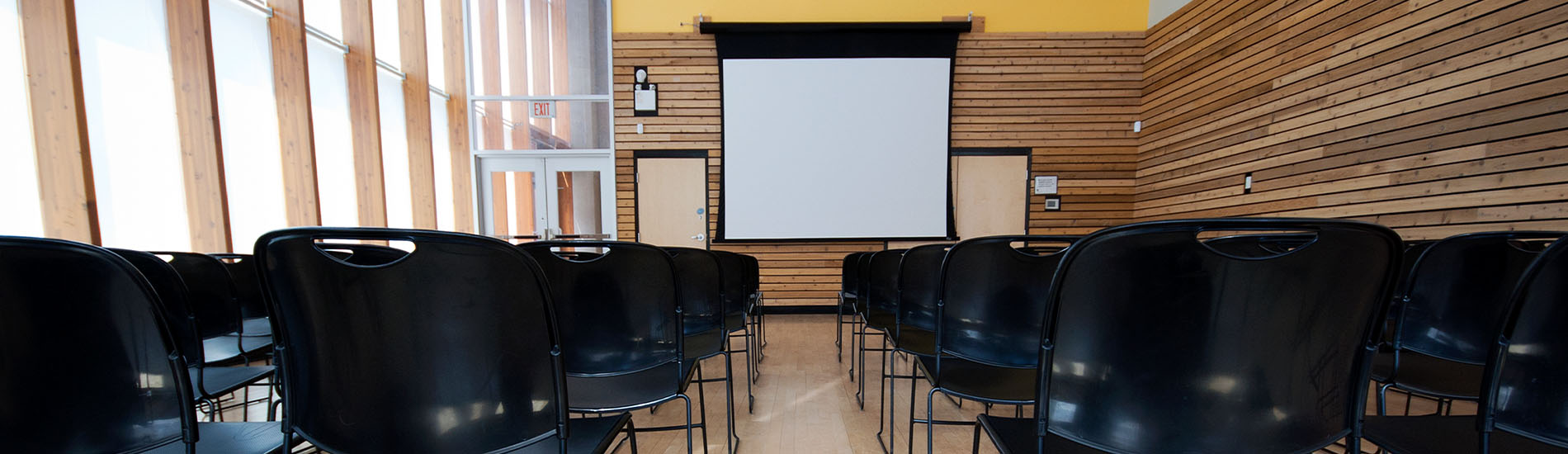 Conference-room-at-NENA-expo-that-is-empty-with-a-lot-of-black-chairs-and-lined-up-to-listen-to-next-gen-9-1-1-presentation-on-blank-white-screen
