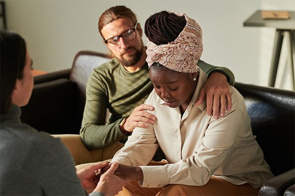 white-male-acting-as-husband-putting-arms-around-african-american-wife-to-console-her-for-mental-support-as-a-call-taker-for-next-gen-9-1-1
