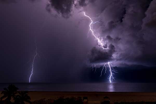 thunderstorms-over-ocean-and-lightning-coming-down-from-sky-into-the-water-showing-a-dangerous-thunderstorm