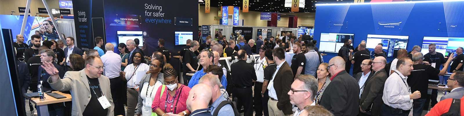 a-lot-of-people-standing-by-different-booths-at-apco-conference-to-talk-about-the-future-of-next-generation-9-1-1-technology-in-emergency-response