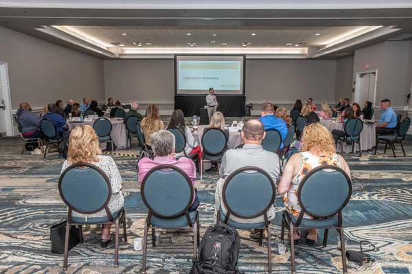 NG9-1-1-professionals-sitting-at-apco-conference-looking-at-slideshow-and-listening-to-speaker-talk-about-the-future-of-next-gen