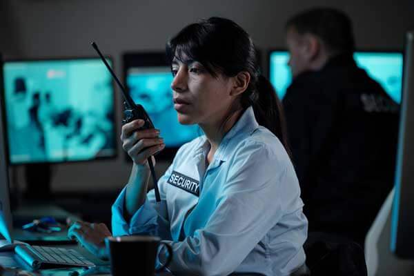 call-taker-talking-with-psap-next-gen-vendors-on-walkie-talkie-looking-at-ng911-data-on-monitor
